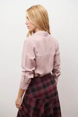 Camisa de mujer a rayas verticales blancas y rosadas, con cuello clásico, cierre de botones frontal y mangas largas con puños abotonados.