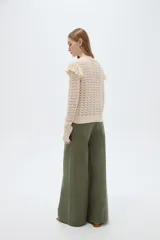Sweater de algodón color natural, de punto con diseño calado, cuello redondo a la base y mangas largas con volados en los hombros.