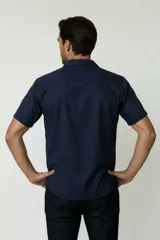 Camisa de manga corta color azul marino, con cuello tipo cubano y cierre frontal de botones.