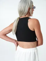 Top negro ajustado al cuerpo, con cuello redondo y cierre frontal con botones.