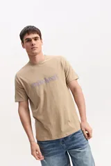 Remera de algodón color beige, de manga corta y cuello redondo, con logo estampado en el pecho en tono morado.
