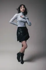 Minivestido negro con cuello alto y mangas largas. Presenta un drapeado lateral con lazos ajustables y un estampado de rosa en el frente.