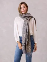 Bufandón de tejido suave con estampado de arabescos en tonos grises y beige, con terminación de flecos en los extremos.