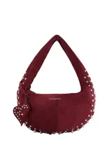 Cartera tipo hobo de Las Oreiro en color bordó, confeccionada en material efecto gamuza. Presenta un diseño de media luna con tachas metálicas plateadas en los bordes y un dije colgante en forma de corazón también decorado con tachas.