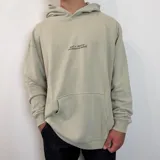 Canguro color verde claro con capucha, corte oversize y estampado gráfico en la espalda con motivos marinos y texto.