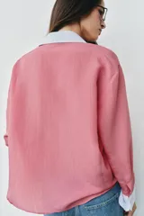 Camisa de rayas finas color rosado, con cuello solapa y puños largos en color blanco a contraste. Presenta cierre frontal con botones y bajo asimétrico con aberturas laterales.