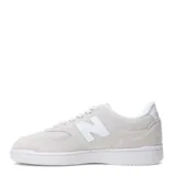 Championes New Balance modelo 080, color gris claro con detalles en blanco. Confeccionados en gamuza y malla, con el logo "N" característico en los laterales y suela de goma blanca.