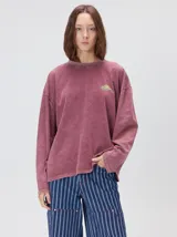 Remera oversize de manga larga color naranja con efecto gastado, cuello redondo y gráfico estampado en la espalda.
