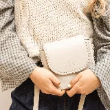 Mini cartera bandolera de cuero, de formato compacto y diseño atemporal con solapa frontal y costuras artesanales decorativas en el borde. Cuenta con el logotipo de la marca grabado en la parte delantera y correa larga regulable.