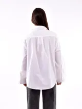 Camisa blanca a rayas verticales color ladrillo, de corte recto y mangas largas con puños abotonados.