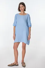 Vestido corto color beige de lino, con cuello redondo, corte oversize y mangas 3/4 con botón. Presenta bolsillos laterales.