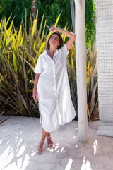 Vestido camisero de muselina color negro, de largo midi, con cuello clásico, manga corta y cierre frontal con botones.