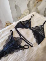 Conjunto de lencería de encaje negro compuesto por un bralette con detalle de aro central y una tanga de doble tira regulable estilo less.