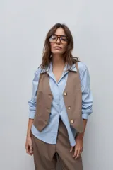 Chaleco sastrero color marrón de escote en V, calce entallado, con botonadura frontal de tres botones y bolsillos de vivo decorativos.