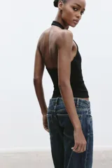 Top de punto con cuello halter y escote redondo profundo, sin mangas y corte ajustado.