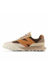Championes urbanos New Balance modelo XC-72, con diseño de paneles en tonos beige, marrón y naranja. Presentan una suela de goma texturizada con diseño dividido y logo N en el lateral.