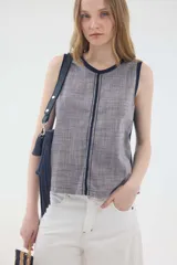 Top sin mangas de algodón texturado en color gris con diseño a rayas sutiles, cuello redondo y ribetes en azul marino. Presenta una costura vertical central con detalles de bordado.
