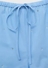 Short de tiro medio color celeste, con cintura elástica, lazo ajustable y detalle de strass aplicado en toda la prenda.