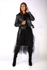 Chaqueta tipo biker de cuero sintético negro, con solapas amplias, cierre frontal asimétrico y detalles de tachas metálicas en las mangas. Incluye cinturón con hebilla en el ruedo.