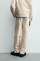 Jeans de hombre color beige claro, tiro medio, corte balloon fit con pierna relajada que se estrecha ligeramente hacia el bajo. Confeccionados en denim rígido de algodón, con cinco bolsillos y cierre frontal de cremallera y botón.