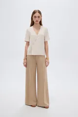 Blusa marrón de manga corta con cuello en V y cierre frontal cruzado con tres botones.