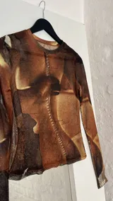 Top de microtul con estampado abstracto en tonos marrones. De manga larga y cuello redondo.