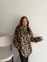 Buzo de peluche con estampado animal print en blanco y negro, de corte holgado, cuello alto y cierre frontal parcial con tirador metálico.