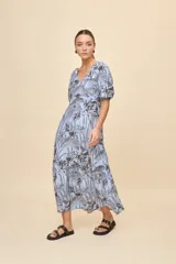 Vestido largo celeste con estampado botánico en tonos marrones, escote en V, mangas cortas abullonadas y falda con volado en el bajo.