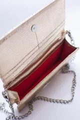 Cartera negra con textura símil cocodrilo y cadena metálica plateada.