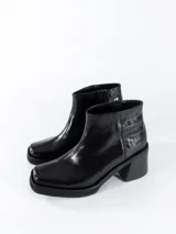 Botas cortas de cuero negro con caña baja y cierre lateral. Presentan puntera cuadrada y taco ancho.