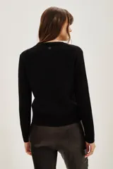 Sweater de punto color negro, con cuello redondo y mangas largas con puños acanalados.
