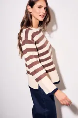 Sweater de punto a rayas horizontales negras y crudas, con cuello redondo y mangas largas. Tiene ribete marrón en puños y ruedo.