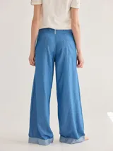 Pantalón jean celeste de corte ancho, con ruedo combinado en un tono más claro.