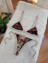 Bikini de dos piezas con corpiño triangular y bombacha de atar, confeccionado en tela de terciopelo elástico con estampado degradé en tonos marrones. El corpiño tiene un broche trasero y breteles regulables, y la bombacha es de corte less brasilero con tiras laterales ajustables.