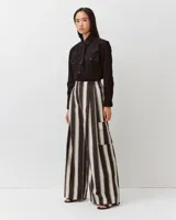 Pantalón amplio de algodón con rayas verticales en tonos negros y blancos, cintura elastizada, corte fluido y grandes bolsillos laterales con solapa de estilo cargo.