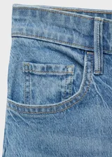 Pantalón jeans de tiro alto y corte wide leg, confeccionado en tejido de algodón con elasticidad. Presenta diseño de cinco bolsillos, cierre frontal con botón y cremallera, y trabillas para cinturón.