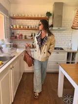 Campera tipo trench corta de gabardina color beige, con diseño de doble botonadura y solapas con forro interior a cuadros. Presenta mangas largas con puños ajustables y corte holgado.