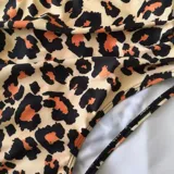 Conjunto de bikini de dos piezas de la marca Uniteduy, compuesto por un crop top amarillo liso con diseño cruzado y tirantes finos, y una bombacha de tiro alto con estampado floral y de hojas en tonos amarillos, verdes y blancos.