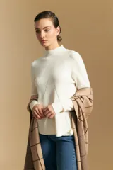 Polera de cuello alto en color blanco, confeccionada en tejido acanalado con un diseño geométrico de relieve que crea un efecto visual estilizado. Presenta un corte al cuerpo y mangas largas, ideal para usar como prenda base o principal.