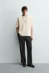 Camiseta de manga corta color crema, con cuello redondo y tejido acanalado verticalmente, de corte holgado (boxy fit).