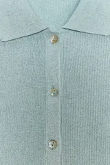 Chaqueta estilo polo de manga larga confeccionada en tejido de punto con hilo metalizado. Presenta cuello solapa y cierre frontal con botones.
