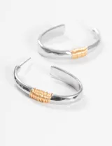 Aros tipo argolla plateados con hilo dorado enrollado.