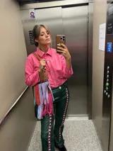 Camisa de cuero color rosado, con cuello clásico, cierre frontal de botones y mangas largas con puños rectos.