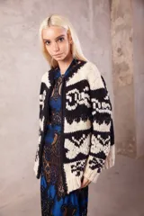 Cardigan de lana tejido a mano con diseño de guardas geométricas en contraste de color blanco y negro. Presenta cuello redondo, cierre frontal y calce holgado.
