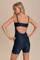 Jumpsuit corto de diseño ajustado con escote cuadrado y breteles finos. Confeccionado en tejido técnico con acabado ligeramente brillante y textura acanalada, ofrece compresión media y alta elasticidad.