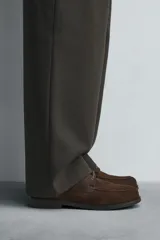 Zapato tipo náutico de hombre, color marrón oscuro, fabricado en piel con acabado serraje (gamuza). Presenta un detalle de bordón en el empeine y suela con ligero tacón.