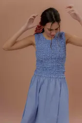 Vestido midi sin mangas de color azul con estampado a cuadros vichy. Presenta la parte superior completamente elastizada y ajustada con efecto fruncido, y falda amplia y suelta.