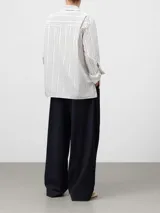 Camisa de corte oversize confeccionada en algodón orgánico, con estampado de rayas verticales. Presenta cuello solapa, manga larga con puños, bolsillo en el pecho y cierre frontal oculto por tapeta.