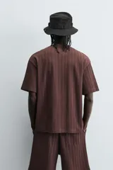 Camiseta de algodón de corte relajado (relaxed fit) color marrón oscuro, con cuello redondo y manga corta. Presenta una textura acanalada vertical tipo jacquard.