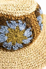 Sombrero de ala ancha color tostado, tejido en papel con detalles de apliques de crochet en la parte central con diseño de flores en tonos celestes, marrones y verde oliva.
